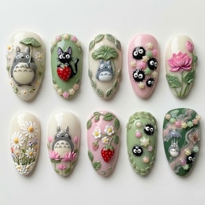 May include: A set of ten almond-shaped nail art designs. Each nail features a different 3D design, including Totoro characters, flowers, strawberries, and soot sprites. The nails are painted in various colors, including white, pink, and green.