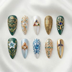May include: A collection of ten almond-shaped press-on nails with various designs. The nails feature intricate details, including gold accents, gems, and symbols. Colors include green, white, gold, and blue. The designs appear to be inspired by a fantasy theme.