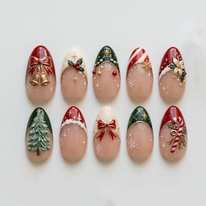 Op de afbeelding: Een set van tien amandelvormige kunstnagels met feestelijke kerstontwerpen. De collectie bevat motieven zoals rode strikken met gouden belletjes, hulst, kerstbomen, zuurstokken, kerststerren en sneeuwvlokken op een nude basis.