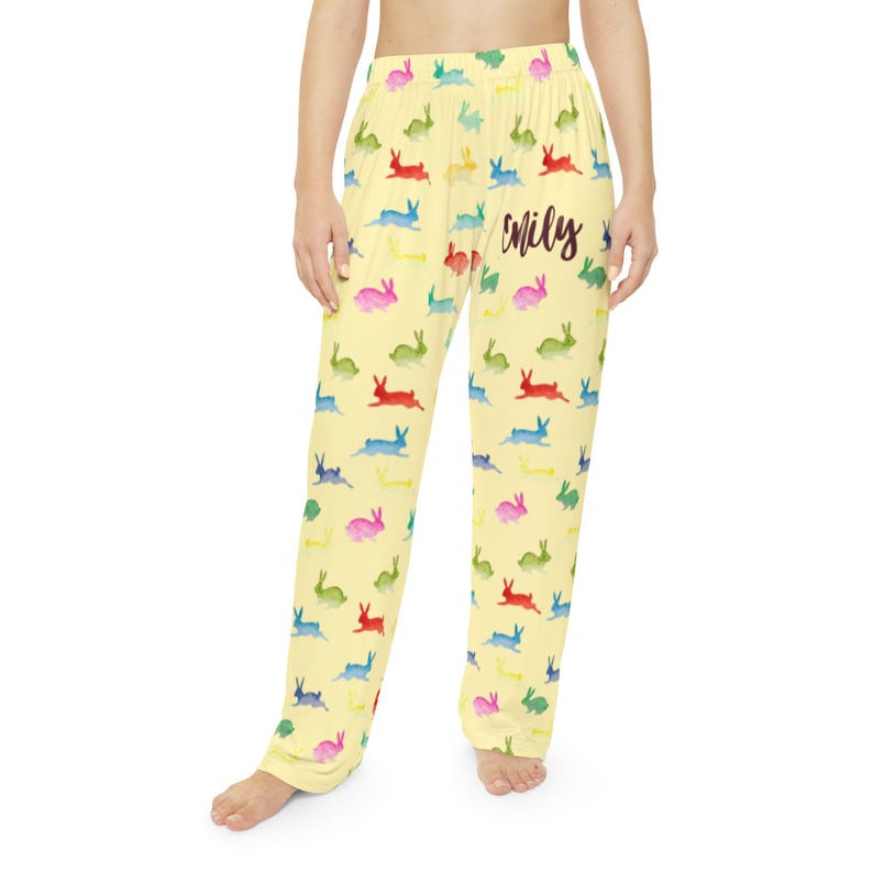 Puede incluir: Pantalones de pijama amarillos con un estampado de conejos coloridos. Los conejos son de color rojo, azul, verde y rosa. El nombre "Emily" est&aacute; escrito en cursiva en los pantalones. Los pantalones son de un material suave y ligero.