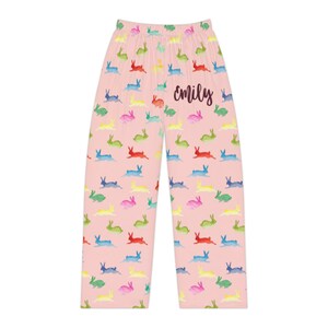 Puede incluir: Pantalones de pijama rosas con un estampado repetido de conejitos coloridos. La palabra "emily" est&aacute; escrita en cursiva en los pantalones. Los conejitos son de color rojo, azul, verde, amarillo y rosa.