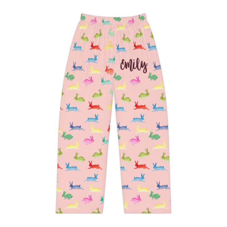 Puede incluir: Pantalones de pijama rosas con un estampado repetido de conejitos coloridos. La palabra "emily" est&aacute; escrita en cursiva en los pantalones. Los conejitos son de color rojo, azul, verde, amarillo y rosa.