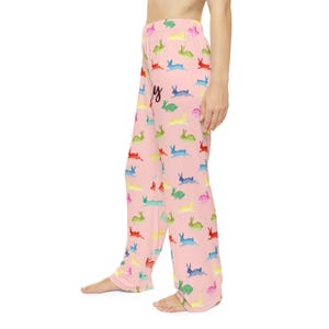 Puede incluir: Pantalones de pijama rosas con un estampado de conejos coloridos. Los pantalones presentan un dise&ntilde;o repetido de conejos en varios colores, incluyendo rojo, azul, verde y amarillo. La palabra "Happy" est&aacute; escrita en cursiva en los pantalones.