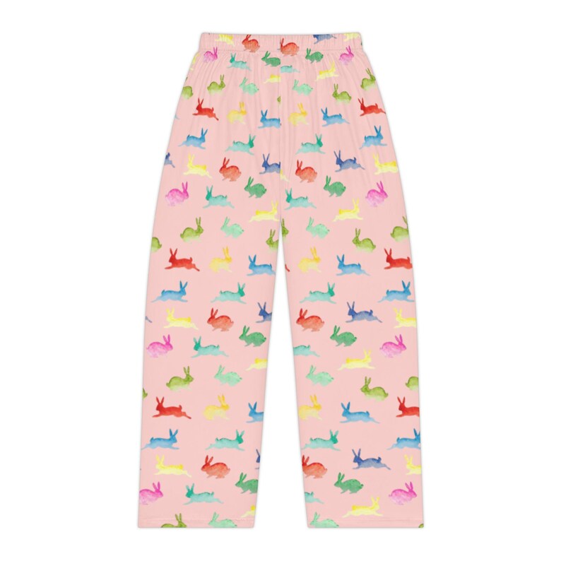 Puede incluir: Pantalones de pijama rosas con un estampado repetido de conejitos de acuarela coloridos. Los conejitos son en tonos de rojo, amarillo, verde, azul y rosa. Los pantalones tienen un corte holgado y un dise&ntilde;o c&oacute;modo.