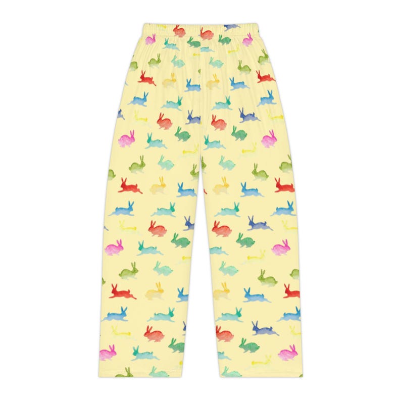 Puede incluir: Pantalones de pijama amarillo claro con un estampado repetido de conejitos de acuarela coloridos en rojo, rosa, azul, verde y amarillo. Los pantalones tienen un corte holgado y un dise&ntilde;o c&oacute;modo.