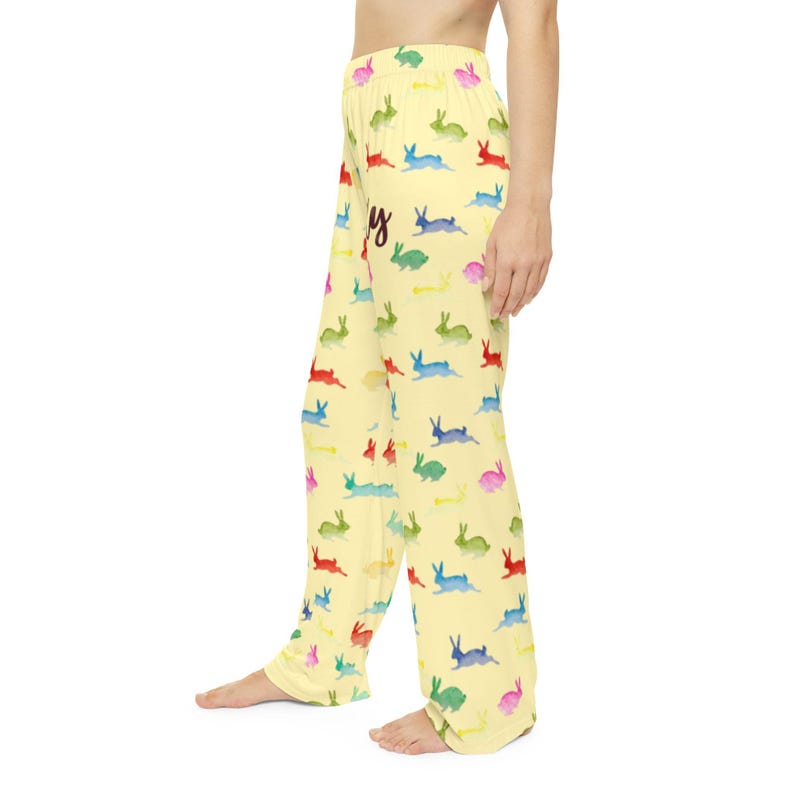 Puede incluir: Pantalones de pijama amarillo claro con un estampado repetido de conejitos de acuarela coloridos. La palabra "Happy" est&aacute; escrita en cursiva en los pantalones. Los pantalones est&aacute;n hechos de una tela suave y fluida.