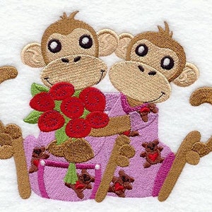May include: Two embroidered monkeys holding a bouquet of red roses. The monkeys are wearing pink and purple pajamas with a heart pattern. The monkeys are holding a bouquet of red roses with green stems and leaves. The monkeys are sitting on a white background.