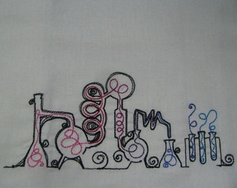 May include: Embroidered design of a science lab with beakers, test tubes, and a complex system of pipes and tubes. The design is done in black, pink, and blue thread.