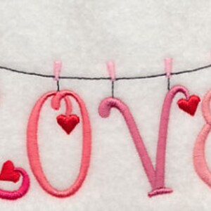 May include: Embroidered design of the word "LOVE" with pink and red hearts hanging from a string with purple envelopes on either side.