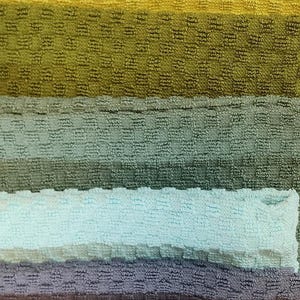 May include: A stack of colorful towels in various shades of orange, yellow, green, blue, pink, brown, and gray. The towels are arranged in a rainbow pattern.