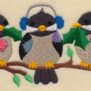May include: Three embroidered birds perched on a branch, each holding a green leaf. The bird in the middle is wearing blue earmuffs. The birds are stitched in shades of grey, blue, purple, and red.
