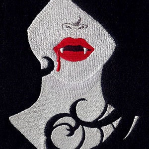 May include: Embroidered patch of a vampire woman with red lips and a single drop of blood dripping from her fangs. The woman has a black and white swirl tattoo on her neck.