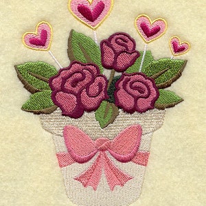 May include: A white ceramic pot with a pink bow holds a bouquet of pink roses and pink hearts.