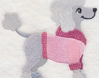 May include: A gray poodle wearing a pink sweater with a white collar. The poodle is standing on all four legs and has a happy expression on its face.