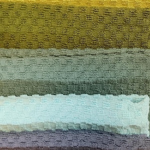 Puede incluir: Una pila de toallas coloridas en varios tonos de naranja, amarillo, verde, azul, rosa, marr&oacute;n y gris. Las toallas est&aacute;n dispuestas en forma de arco&iacute;ris.