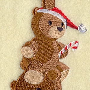 May include: A stack of three brown teddy bears with embroidered details. The top bear is wearing a green scarf, the middle bear is wearing a red and white Santa hat, and the bottom bear is wearing a red sweater.