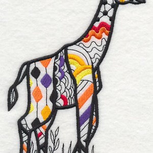 May include: Embroidered giraffe design with a black outline and colorful geometric patterns. The giraffe features orange, yellow, purple, and red accents. The giraffe is standing on a patch of grass.