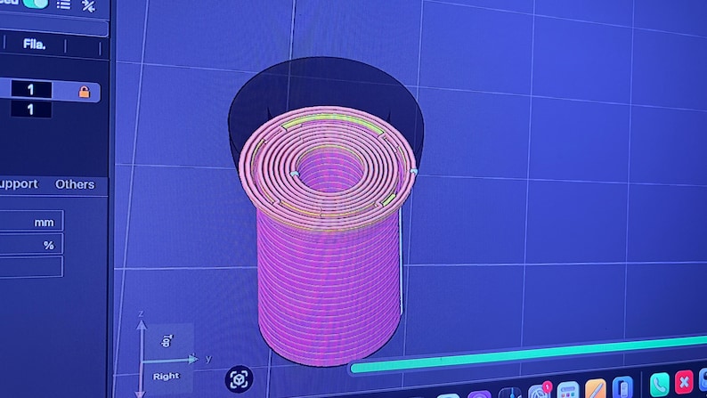 K&ouml;nnte beinhalten: Ein 3D-Modell eines zylindrischen Objekts mit Spiraldesign, in Rosa- und Gelbt&ouml;nen gerendert. Das Modell wird auf einem blauen Bildschirm mit einem Rastermuster angezeigt, wahrscheinlich eine CAD- oder 3D-Modellierungssoftware-Oberfl&auml;che.