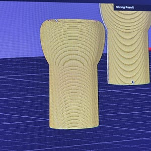 K&ouml;nnte beinhalten: Zwei gelbe, zylindrische Objekte mit abgerundeten Oberteilen werden vor einem blauen Gitterhintergrund dargestellt. Die Objekte scheinen 3D-Modelle oder Prototypen zu sein, m&ouml;glicherweise f&uuml;r ein Designprojekt. Der Text "Slicing Result" ist oben im Bild zu sehen.