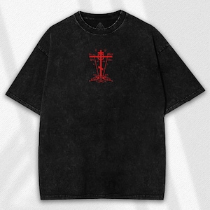 May include: Black t-shirt with a red graphic of a cross. The t-shirt has a crew neck and short sleeves. The graphic is centered on the chest and features a stylized cross design with ornate details.