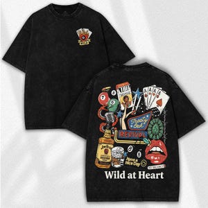 May include: Black graphic tee with a vintage-style design. The front features a playing card symbol with the word "WILD". The back displays a collage of images including playing cards, a bottle of whiskey, and the text "Wild at Heart".
