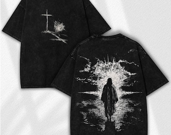 May include: Black t-shirt with a distressed look. The front features a cross and a tree graphic. The back displays a figure walking towards a bright light. The shirt has short sleeves and a crew neck.