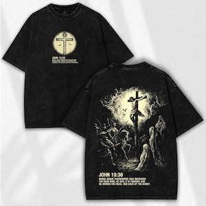 May include: Black t-shirt featuring a religious design. The front displays a cross within a circle, with the text "JOHN 19:30" and a Bible verse. The back showcases a crucifixion scene with the same text and verse.