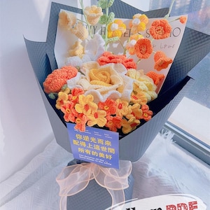 May include: A bouquet of crocheted flowers in shades of yellow, orange, and white, wrapped in black paper and tied with a peach ribbon. The bouquet includes a card with text in Chinese and English. The words "Pattern PDF" are visible.