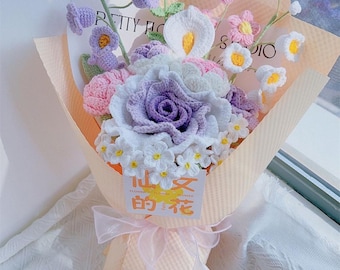 以下が含まれることがあります： 紫、ピンク、白、黄色の手編みの花のブーケ。 桃色の紙で包み、ピンクのリボンで結ばれています。 バラやカラーなど、さまざまな種類の花が含まれています。