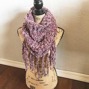 May include: A mauve velvet infinity scarf with fringe. The scarf is displayed on a mannequin.