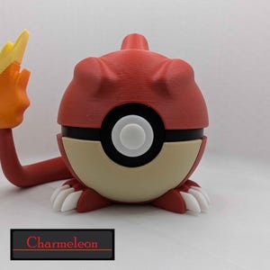 Puede incluir: Figura de Charmeleon rojo y beige con una llama en la cola. La figura tiene garras blancas y un diseño de círculo blanco y negro. La palabra "Charmeleon" está escrita en rojo sobre un rectángulo negro.