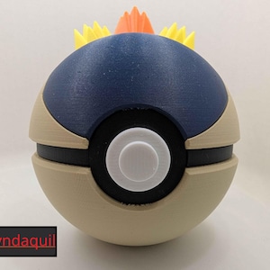 May include: A 3D-printed Cyndaquil-themed Poke Ball. The ball features a navy blue top, tan midsection, and a black band with a white center. Spikes of yellow and orange adorn the top. The text "Cyndaquil" is in a black box.