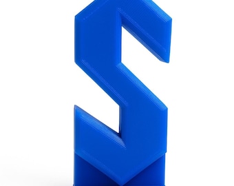 May include: A vibrant blue, geometric letter "S" sculpture. The letter is constructed from angular, connected planes, creating a modern, three-dimensional design. The sculpture stands upright on a small base, showcasing a bold, solid color.