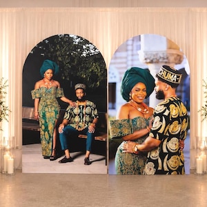 May include: Two large arched display panels featuring printed photographs of a couple in traditional attire. The left panel shows a person in a green patterned dress and a person in a matching shirt and trousers. The right panel shows the same couple.