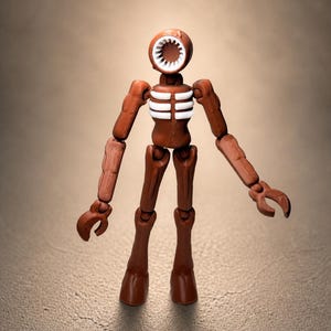 May include: A brown articulated figure with a circular head featuring a toothed mouth and a white interior. The figure has a rib cage design and claw-like hands. The figure is standing on a textured surface.