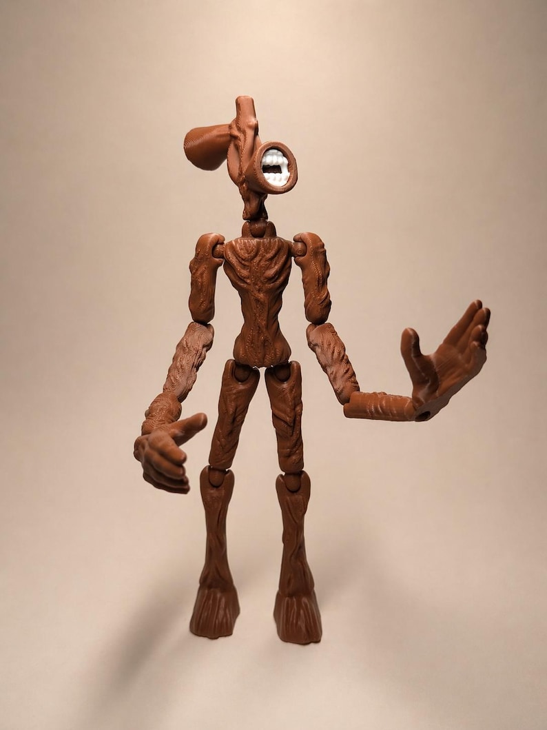 Puede incluir: Figura de acci&oacute;n de Siren Head marr&oacute;n con articulaciones. La figura tiene una cabeza con forma de altavoz con boca blanca y un cuerpo delgado y texturizado. Los brazos est&aacute;n extendidos y la figura se apoya en dos piernas con forma de tronco de &aacute;rbol.