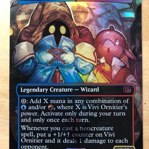 May include: A rectangular trading card featuring the character Vivi Ornitier in a blue coat and brown hat alongside a pink creature. The card displays the text Vivi Ornitier, Legendary Creature - Wizard, and game rules with a 0/3 power and toughness.