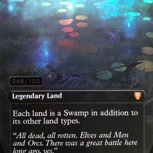 May include: A collectible trading card titled The Dead Marshes, featuring a dark, swampy illustration with glowing lily pads and a submerged figure. The card text reads: Each land is a Swamp in addition to its other land types. All dead, all rotten.