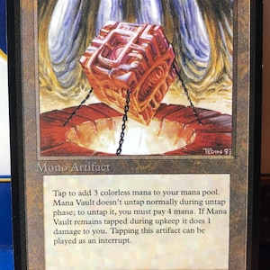 May include: A Magic: The Gathering trading card titled Mana Vault, featuring an illustration of a glowing orange cube suspended by chains over a circular pit. The card text reads Mono Artifact and details its game mechanics, with the artist credit Mark Tedin.