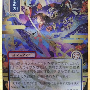 May include: A Japanese language Magic: The Gathering trading card titled 意志の力 featuring a character with long dark hair holding a sword. The card has a blue and purple color palette with gold accents, a mana cost of 300, and text describing the card's ability.