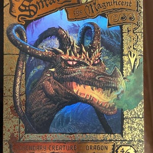Pode incluir: Um cartão colecionável retangular apresentando Smaug, o Magnífico, um dragão marrom com olhos vermelhos brilhantes e fumaça saindo de sua boca. O cartão tem uma borda dourada com texto preto, incluindo Legendary Creature - Dragon.