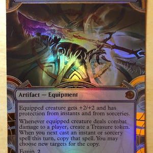 May include: A holographic Magic: The Gathering trading card titled Sword of Wealth and Power. The card features an illustration of a sword, with text detailing its artifact equipment abilities, including +2/+2, protection, and token creation.