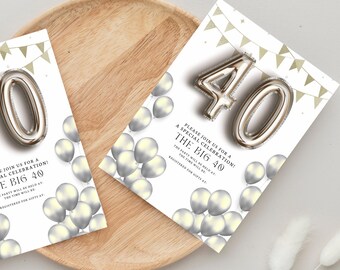 Op de afbeelding: Twee witte uitnodigingskaarten met zilveren ballonnen en de tekst "THE BIG 40". Zilveren cijferballonnen spellen "40". De kaarten liggen op een houten dienblad met een witte achtergrond. De kaarten hebben gouden bannerversieringen.