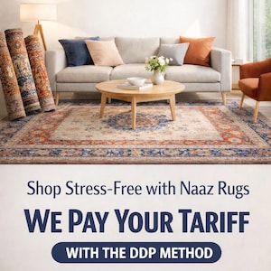 Puede incluir: Escena interior con sof&aacute; beige, cojines coloridos, mesa de centro redonda de madera y alfombra estampada. Alfombras enrolladas a la izquierda. El texto "Naaz Rugs" en la parte superior.