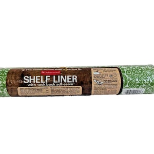 May include: A roll of Rubbermaid shelf liner with a tack back adhesive. The label reads "SHELF LINER" in large white letters. The liner has a brown wood-grain pattern and a green and white floral design.