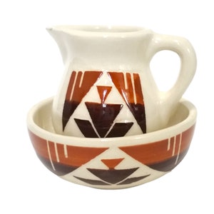 May include: A white ceramic pitcher and bowl set with a geometric pattern in brown and orange. The pitcher has a handle and the bowl is round.