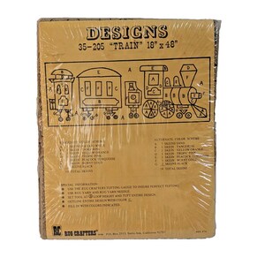May include: A brown paper pattern for a rug hooking project. The pattern is for a train with a caboose and several cars. The pattern includes instructions for the colors and materials needed to complete the project. The pattern is labeled "Designs 35-205 "Train" 18" x 48"