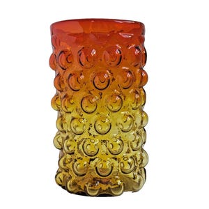 May include: A vintage glass vase with a textured surface of raised, circular bubbles. The vase transitions from a deep orange at the top to a golden yellow at the base. The cylindrical shape is ideal for displaying flowers or as a decorative piece.