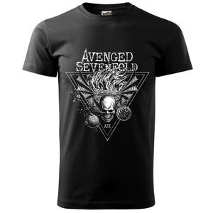 Peut inclure: T-shirt noir avec un motif blanc représentant un crâne avec des ailes, des flammes et le texte "AVENGED SEVENFOLD" à l'intérieur d'un triangle. Le design comprend les lettres "ATX". Le t-shirt est de style col rond.