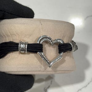 K&ouml;nnte beinhalten: Eine wei&szlig;e Keramik-Tasse mit schwarzem Henkel und dem Text "But First, Coffee" in fetter, schwarzer Schrift. Die Tasse steht vor einem neutralen Hintergrund, der ihr schlichtes Design hervorhebt.